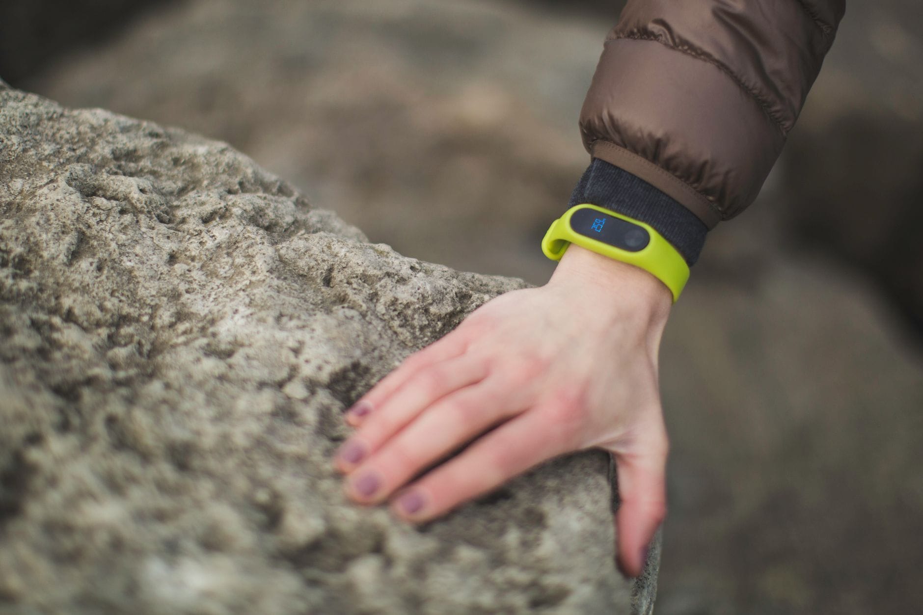 Jak technologia wearables pomaga monitorować zdrowie i aktywność Twojego psa Dłoń z opaską fitness dotykająca skały w plenerze